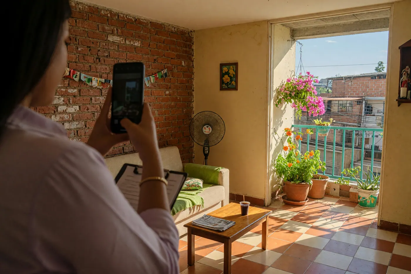 A person doing an apartment inspection walkthrough in a sunlit Colombian apartment with tiled floors and a balcony.