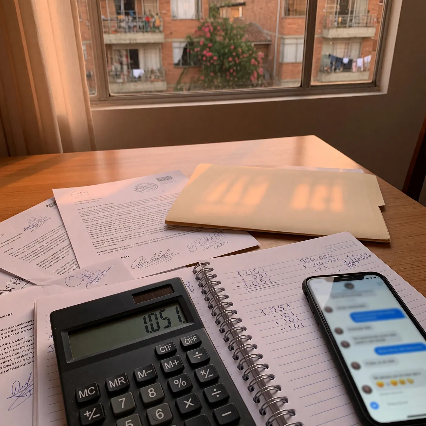 Lease agreement and calculator on a table with handwritten rent calculations