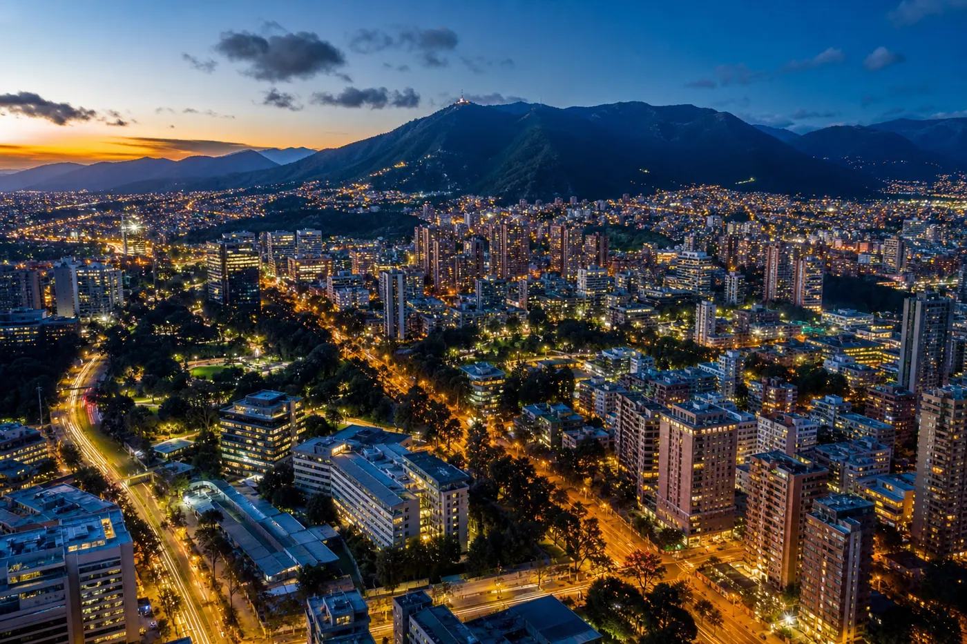 Aerial view of Bogotá, Colombia at dusk — northern neighborhoods glowing with city lights, Andes mountains silhouetted in the background