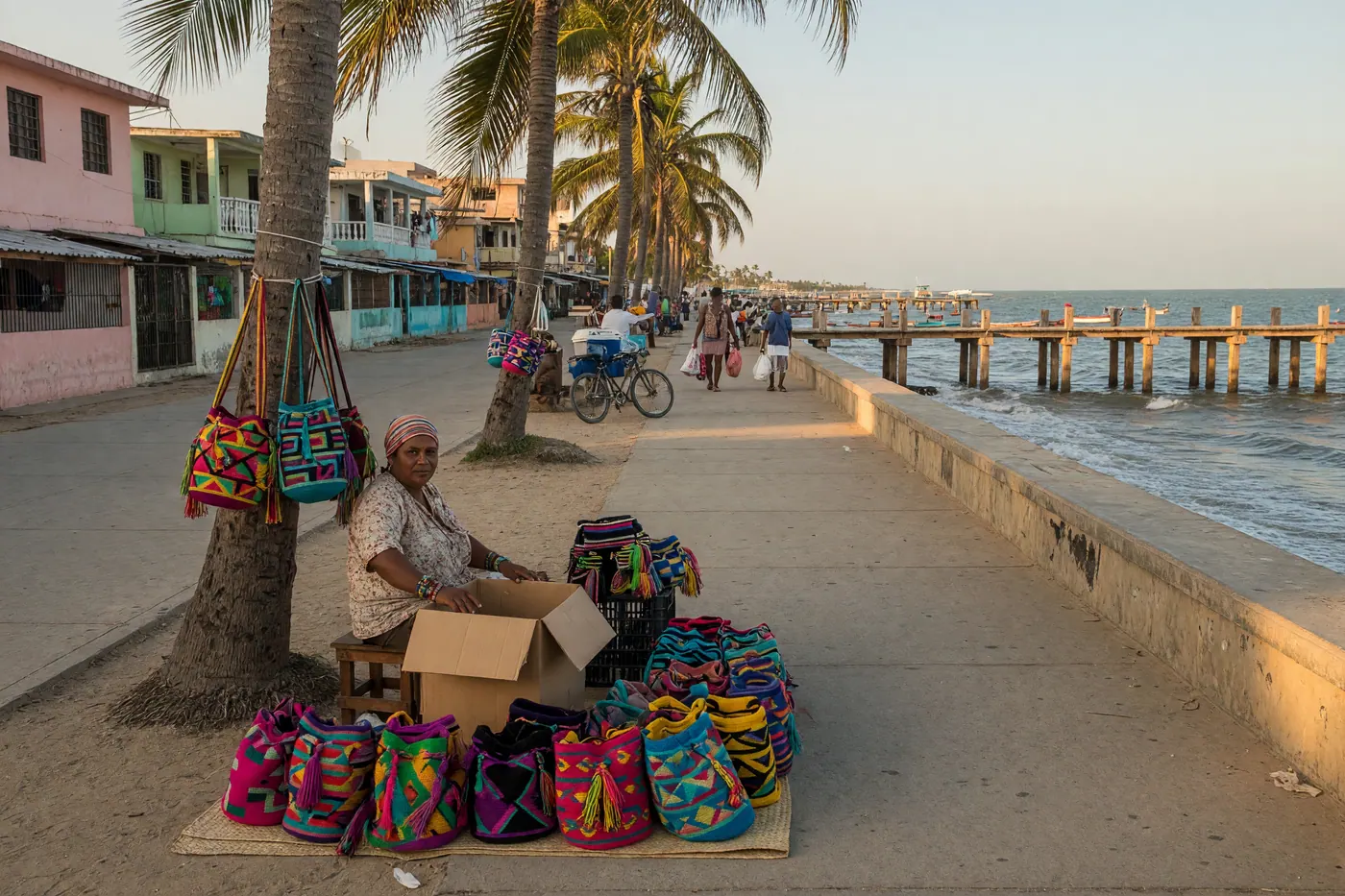 Vista amplia del muelle de madera de Riohacha al atardecer, con el mar Caribe y palmeras.