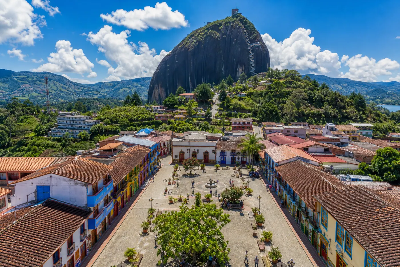 Aerial view of Guatapé's colorful zócalo-painted streets with El Peñón granite rock in the background, Antioquia, Colombia