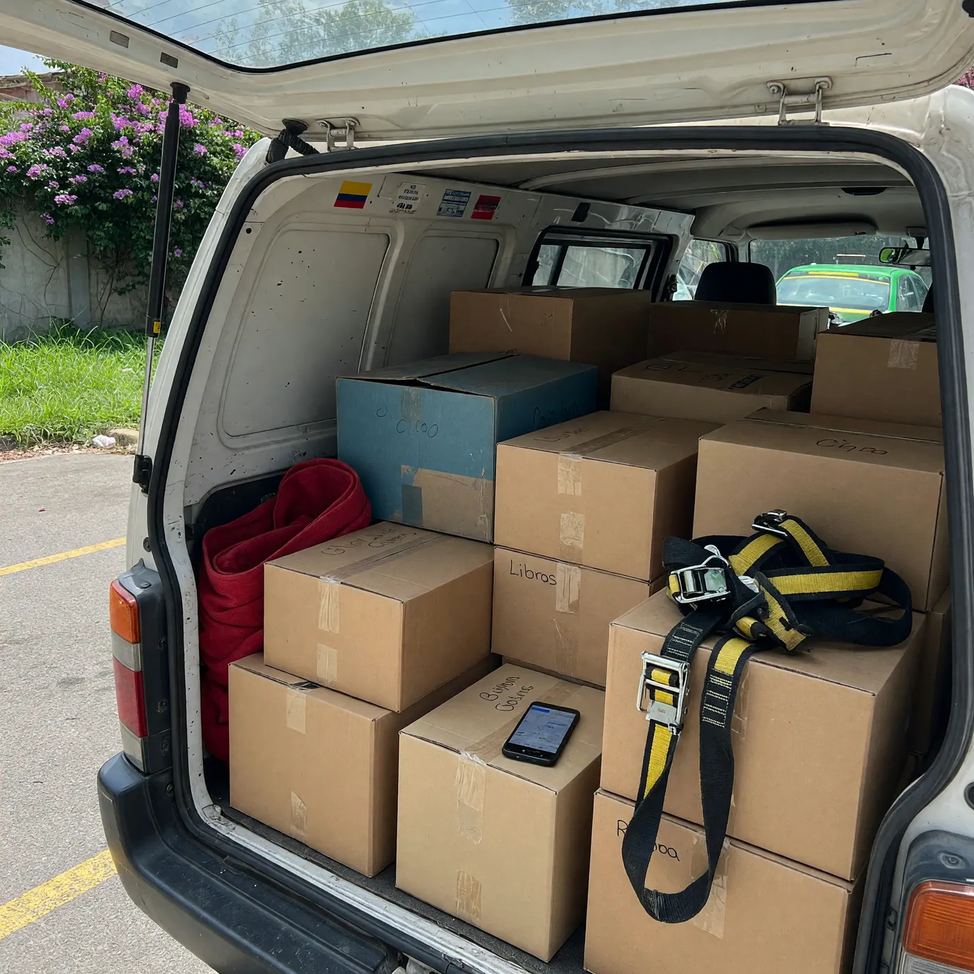 Baúl de un vehículo en Colombia cargado con cajas de mudanza y correas, listo para un acarreo local