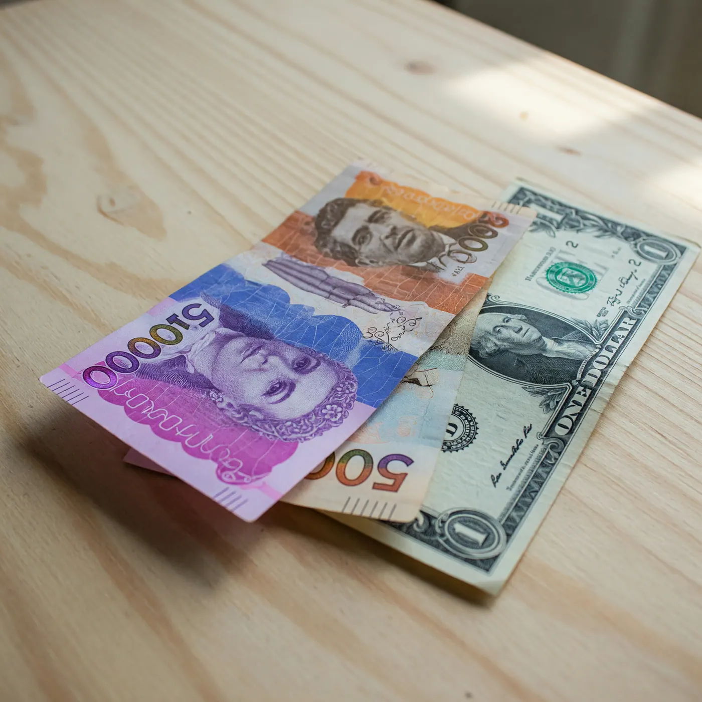 Billetes de pesos colombianos junto a un dólar estadounidense