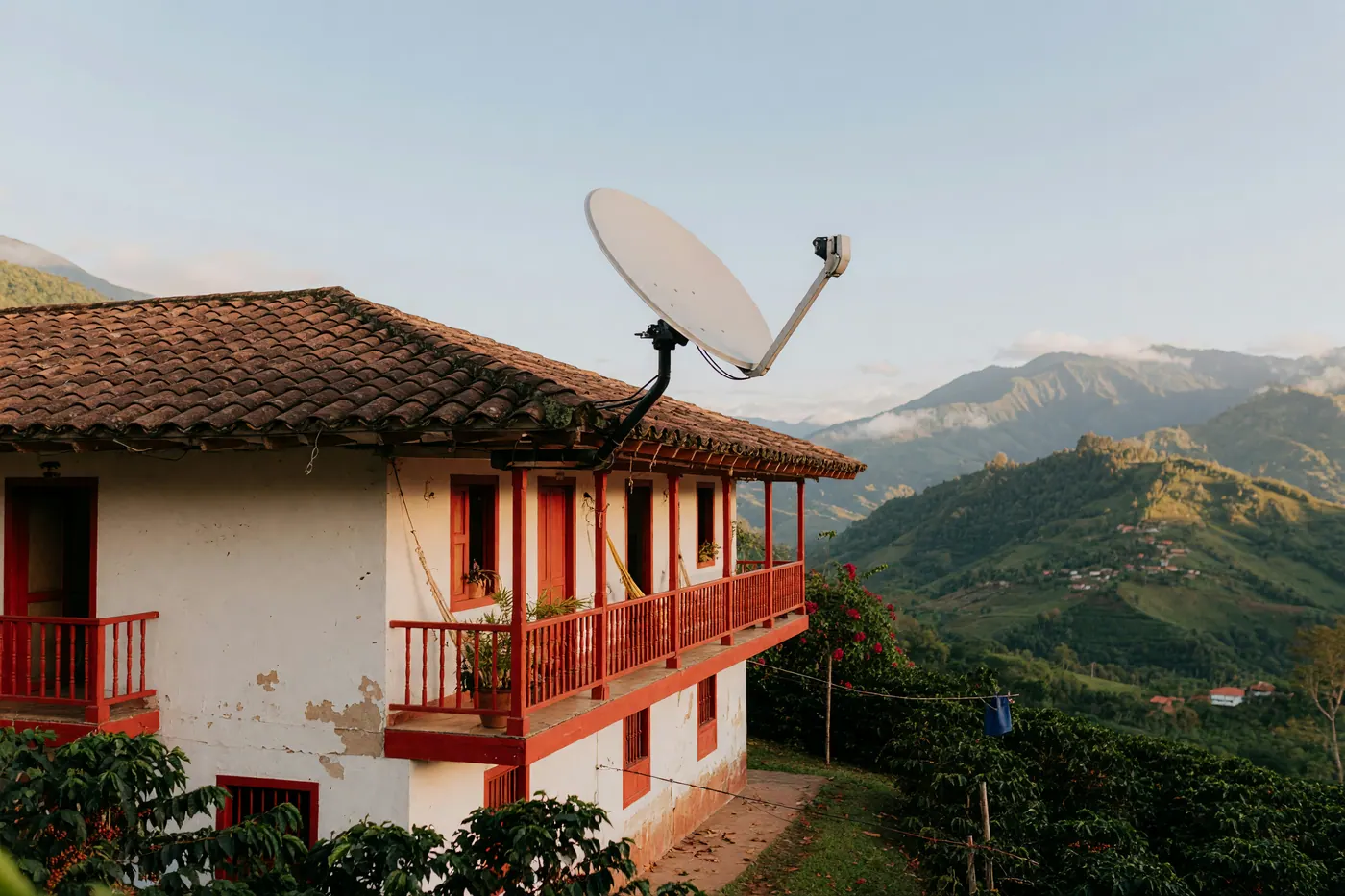 Satellite internet antenna mounted on the clay tile roof of a rural Colombian finca overlooking green Andean mountains