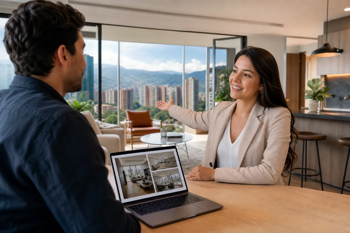 Real estate agent showing a client around a modern apartment in Medellín with laptop and listing photos on the table