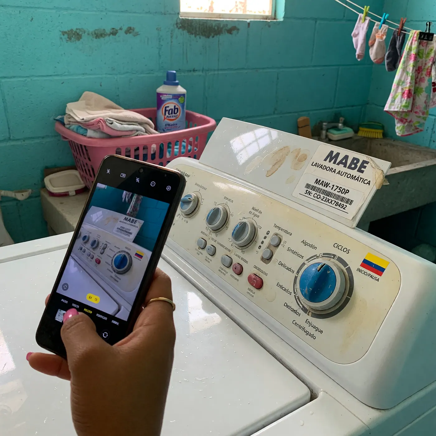 Persona tomando con el celular una foto clara de la placa de modelo de una lavadora usada