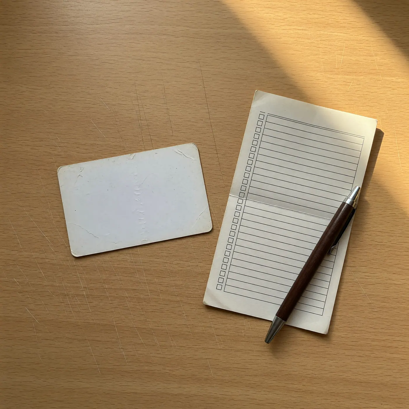 Tarjeta de identidad boca abajo, lista de verificación y bolígrafo sobre una mesa de madera