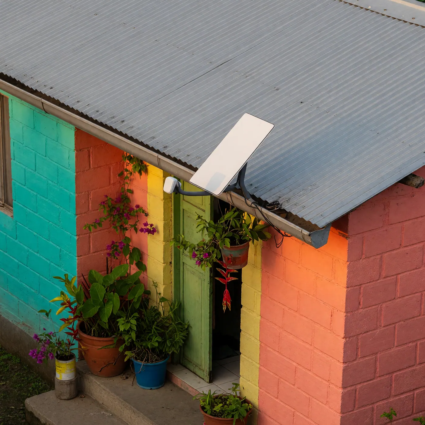 Fachada de casa colorida en el casco urbano de Inírida con techo de zinc y antena de internet satelital bajo la luz del día