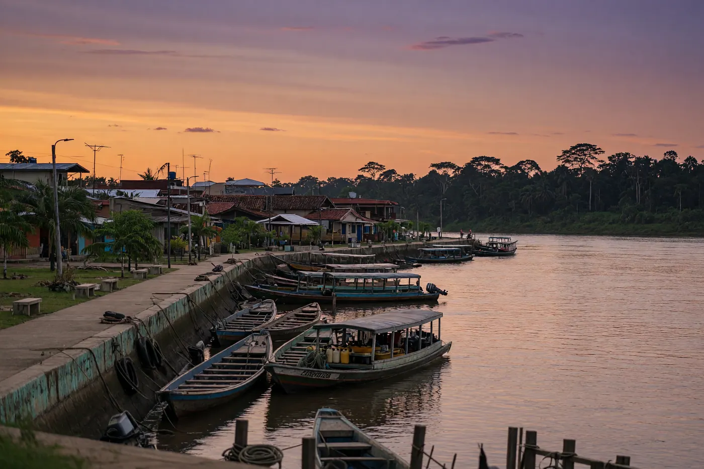 Malecón de Leticia al atardecer sobre el río Amazonas con lanchas de madera y selva al fondo