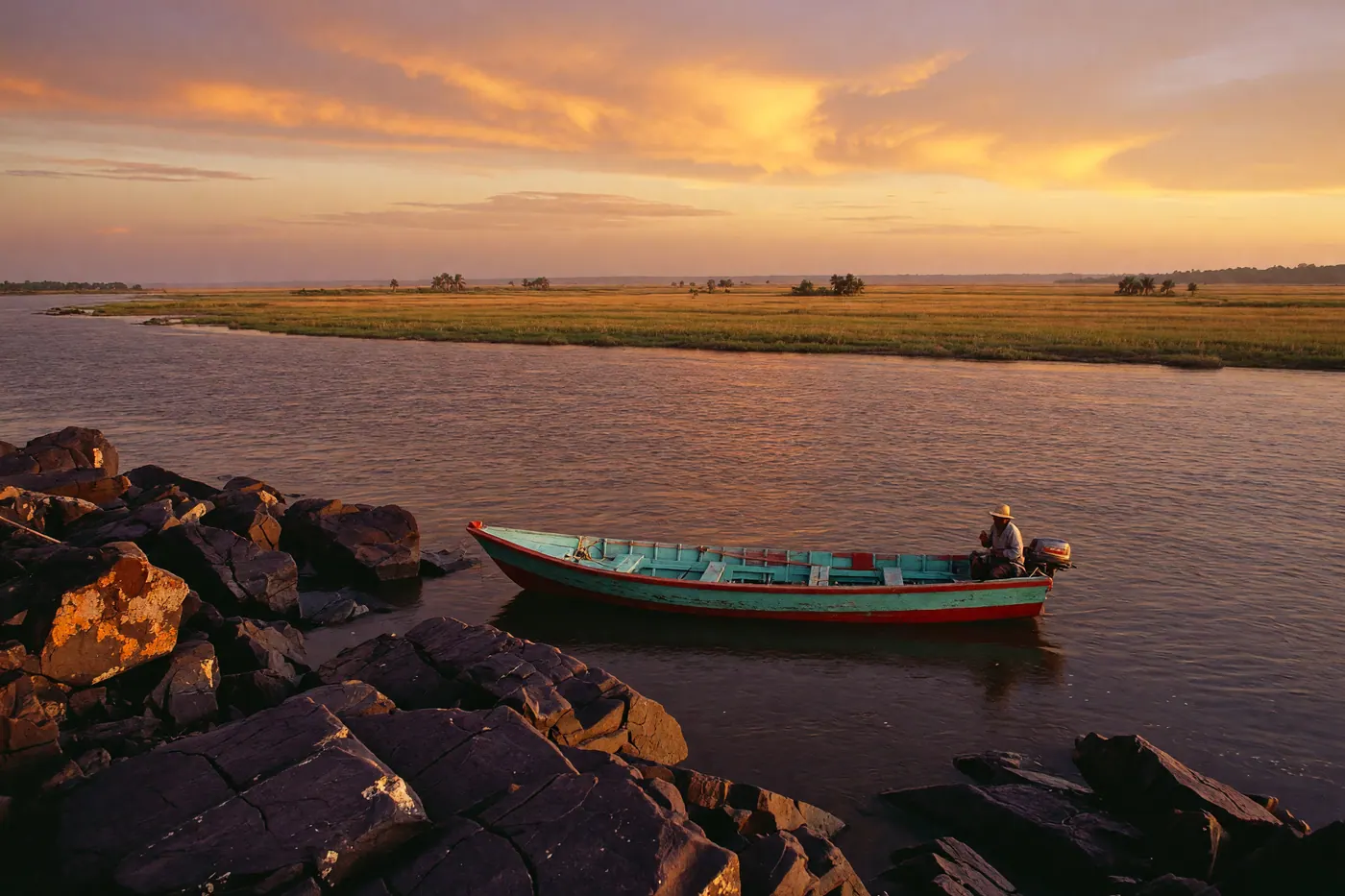 Un planchón de madera flotando en el río Orinoco cerca de la orilla rocosa de Puerto Carreño durante un atardecer dorado en el Vichada
